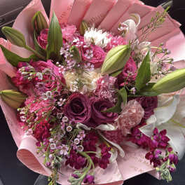 Pink and white bouquet with roses, lilies, and carnations wrapped in pink paper