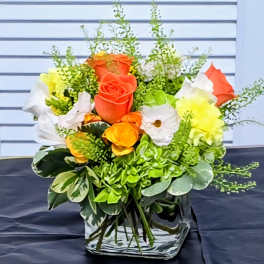 Bouquet of orange, white, and yellow roses in a clear vase