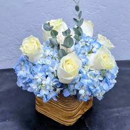 White roses and blue hydrangeas in a wooden basket