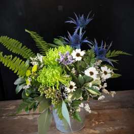 Mixed bouquet with green chrysanthemums, white daisies, and blue thistle in a metal bucket