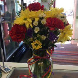 Bouquet of red and yellow flowers in a glass vase with ribbon