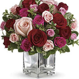 Bouquet of red, pink, and blush roses in a clear square vase