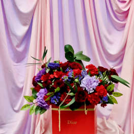 Red and purple flower arrangement in a red Dior box