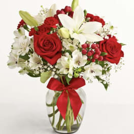 Bouquet of red roses, white lilies, and red carnations in a glass vase