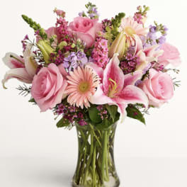 Pink roses and lilies arranged in a clear glass vase