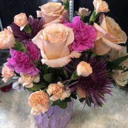 Peach roses and pink carnations in a lavender vase