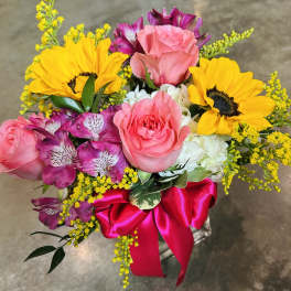 Bouquet of pink roses, sunflowers, and purple alstroemeria with a pink ribbon