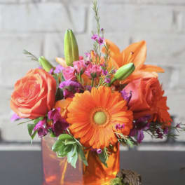 Orange roses and gerbera daisies in a glass vase