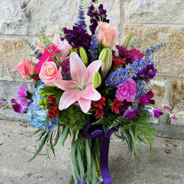 Colorful bouquet with pink lilies, roses, and purple flowers in a vase