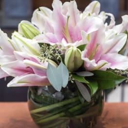 Pink and white lilies arranged in a glass vase