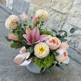 Pink lilies and peach roses in a white vase with a satin ribbon