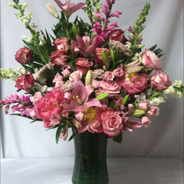 Pink mixed flower arrangement in a tall green vase