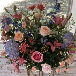 Large mixed floral arrangement with roses, lilies, hydrangeas, and blue flowers