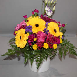 Bright mixed bouquet in a white vase with yellow daisies and pink blooms