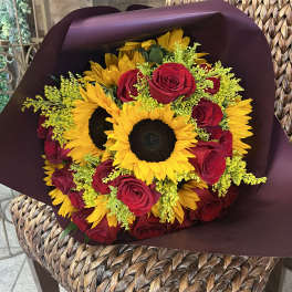 Bouquet of red roses and yellow sunflowers wrapped in dark paper