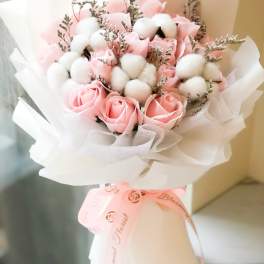 Pink roses and white cotton stems in a wrapped bouquet