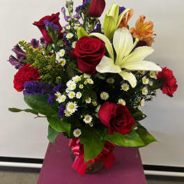 Mixed bouquet of red roses, white lilies, and purple filler flowers in a vase