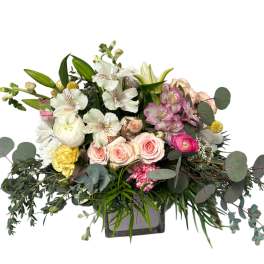 Mixed bouquet of roses, lilies, and alstroemeria in a square vase