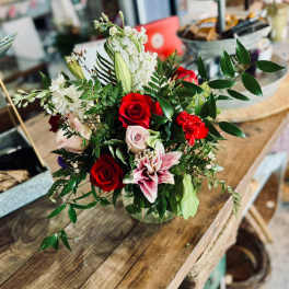 Mixed bouquet of red and pale pink roses with white blooms in a glass vase