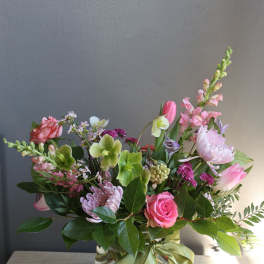 Mixed pink and green flower arrangement in a glass vase with a ribbon