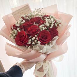 Bouquet of red roses and white baby's breath wrapped in pink paper
