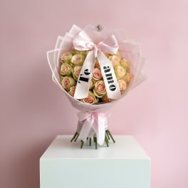 Bouquet of pale pink roses wrapped in pink paper with a satin bow