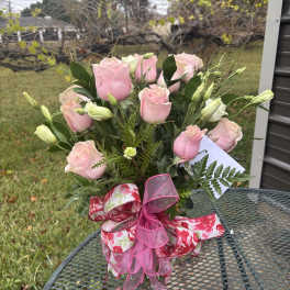 Pink roses arranged in a clear vase with pink ribbon