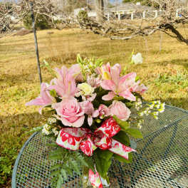 Pink lilies and roses in a glass vase with a floral ribbon