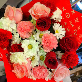 Bouquet of red and pink roses with white daisies and carnations in red wrap