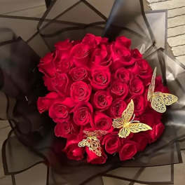 Bouquet of red roses wrapped in dark paper with butterfly decorations