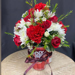 Red and white flower arrangement in a Dr Pepper can with a ribbon