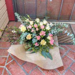 Bouquet of pink and cream roses with eucalyptus in kraft paper