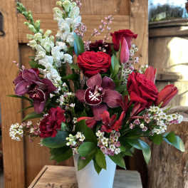 Red roses and burgundy orchids in a white vase