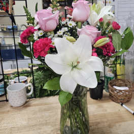 Pink roses and carnations with a large white lily in a glass vase