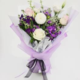 Bouquet of white and purple flowers wrapped in lavender paper