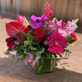 Bright pink and red mixed bouquet in a green glass vase