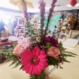 Mixed bouquet in a decorative tin with pink and purple flowers and butterfly picks
