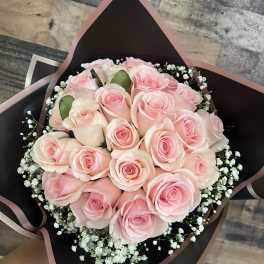 Bouquet of pale pink roses with baby's breath in black wrap