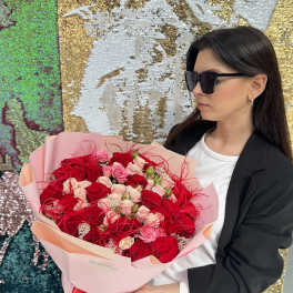 Woman holding a large bouquet of red and pink roses wrapped in pale pink paper