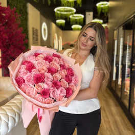 Woman holding a large bouquet of pink roses wrapped in pale pink paper