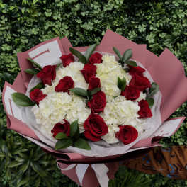 Bouquet of red roses and white hydrangeas wrapped in pink paper
