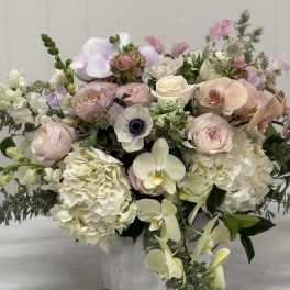 Pastel bouquet with roses, hydrangeas, orchids, and anemones in a white vase