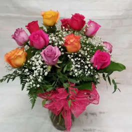 Bouquet of multicolored roses in a glass vase with pink ribbon