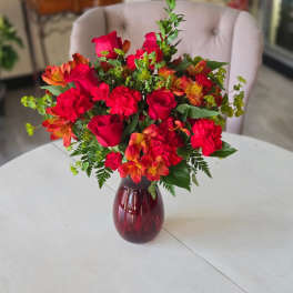 Bouquet of red roses and orange alstroemeria in a burgundy vase