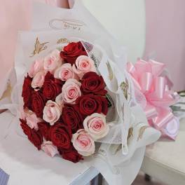 Bouquet of red and pale pink roses wrapped in white paper