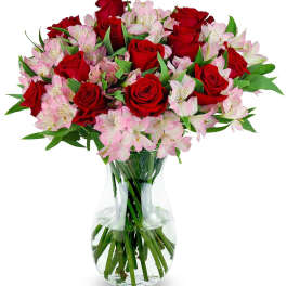 Vase arrangement of red roses and light pink alstroemeria in a clear glass vase
