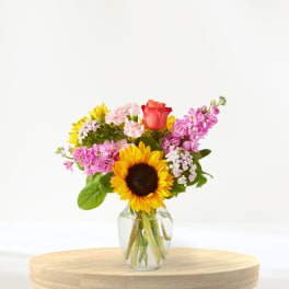 Mixed bouquet with a sunflower and rose in a clear glass vase