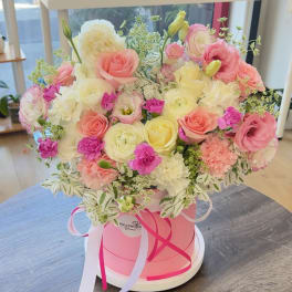 Pink and cream rose bouquet in a round pink box with ribbons