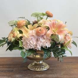 Peach and blush floral arrangement in a gold pedestal vase