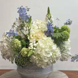 White and blue floral arrangement in a gray bowl vase
